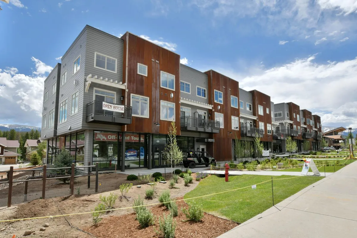 This exterior image showcases modern building architecture with an open house sign and beautifully landscaped gardens. The inviting entrance and visible pathways evoke a sense of community and easy access to outdoor adventures.