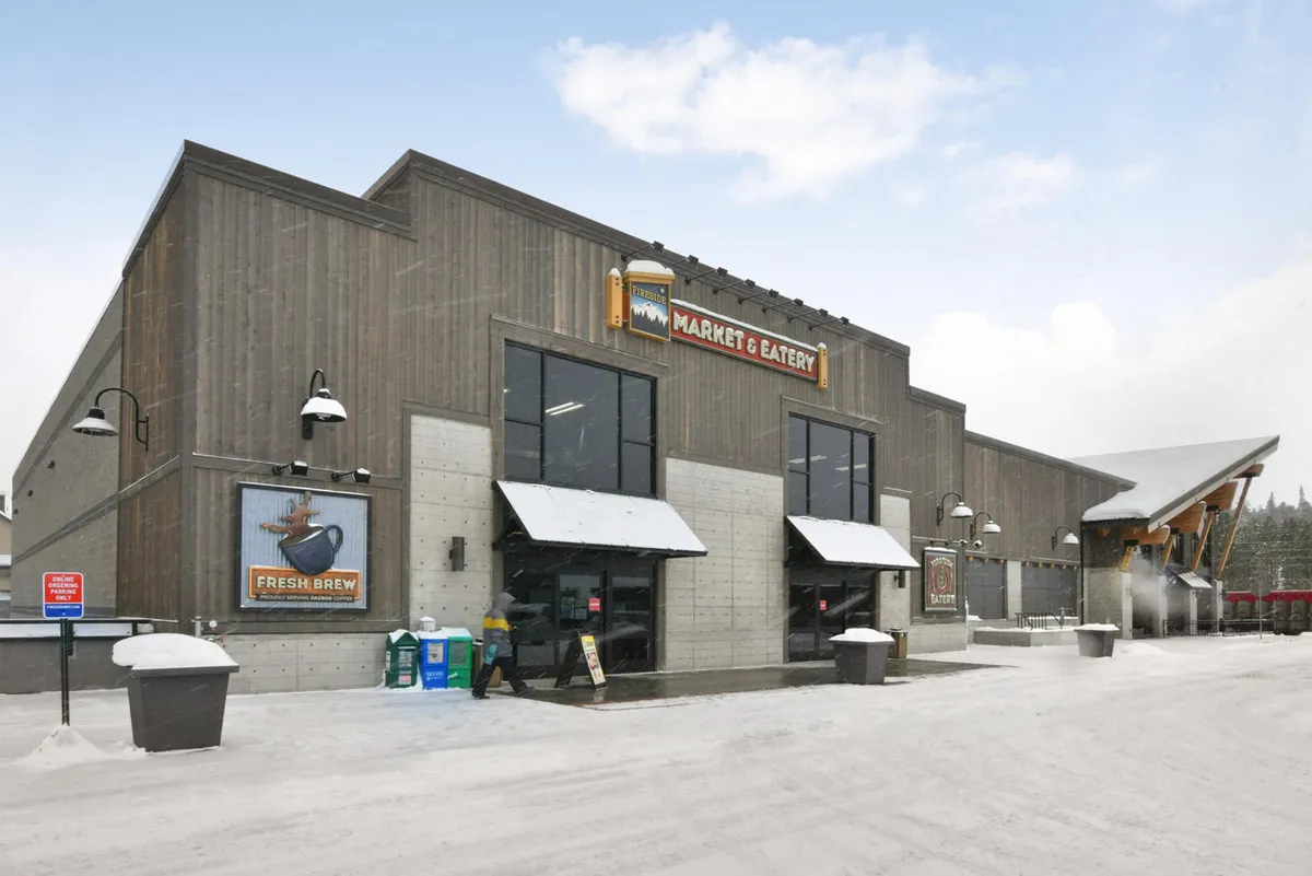 A welcoming exterior shot of a large wooden structure with a visible market sign and snow-covered entrance. The inviting scene hints at local charm, with opportunities for boutique shopping, gourmet dining, and cozy community experiences right outside the property.