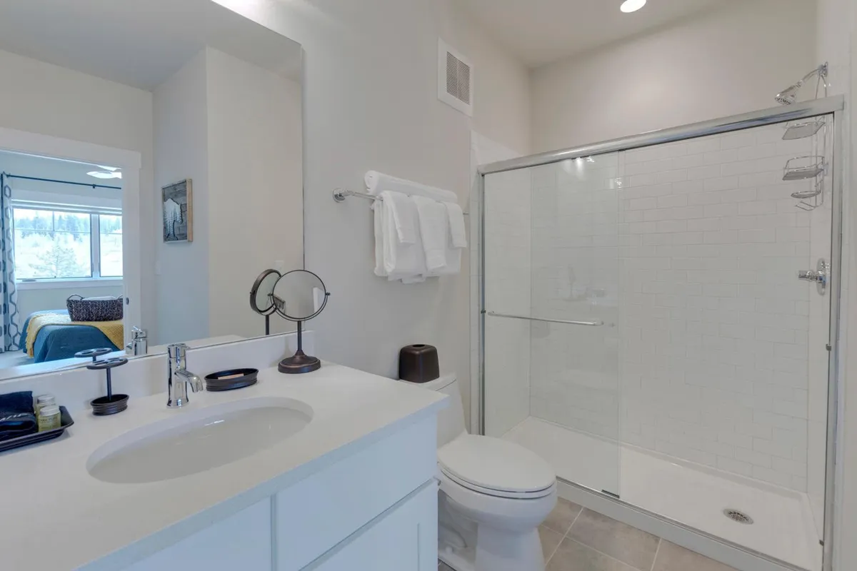 A modern bathroom with a vanity sink, shower enclosure, and a well-lit mirror. The space feels clean and inviting, perfect for self-care routines and refreshing after outdoor adventures.