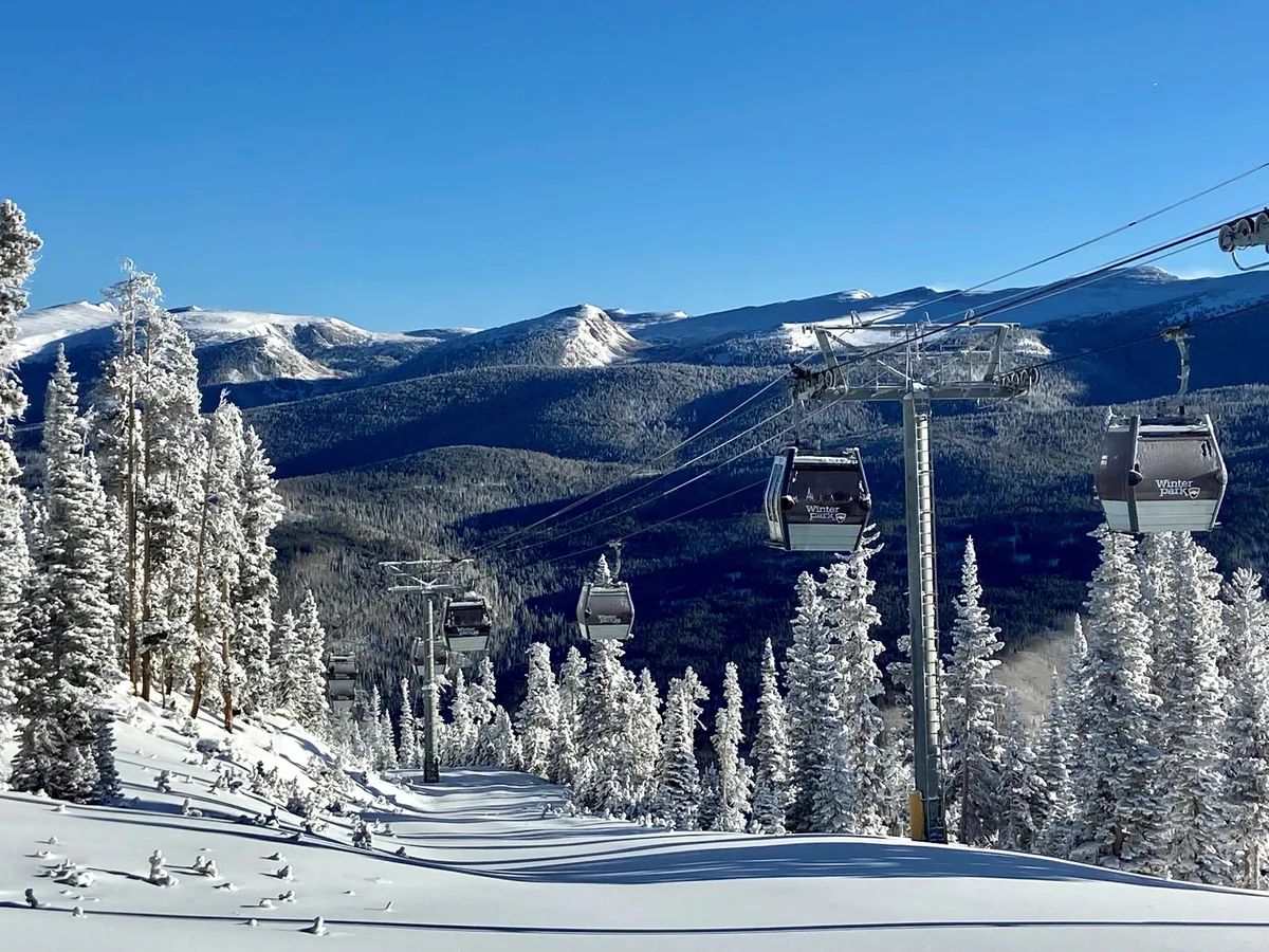 A striking exterior view featuring a ski lift ascending through snow-covered trees and a majestic mountain range in the distance. The scene captures the thrill of alpine activities and the allure of the surrounding landscape, inviting guests to experience winter sports and mountain adventures.